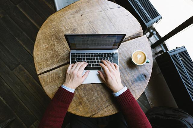 man reading at a computer in a coffee shop