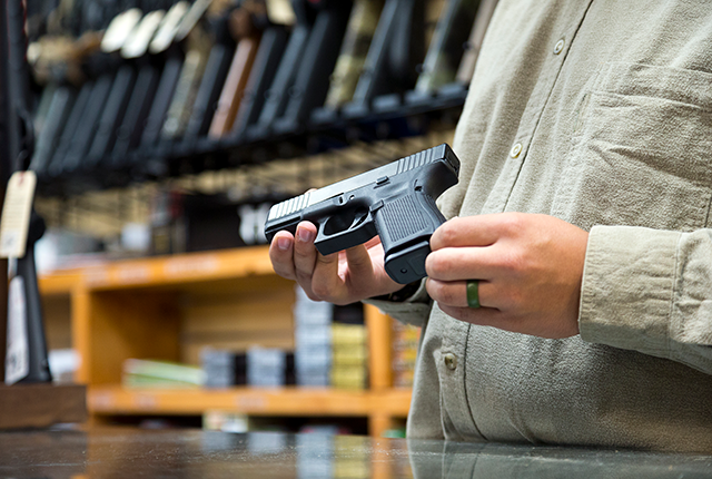 picture of gun shop employee displaying a handgun