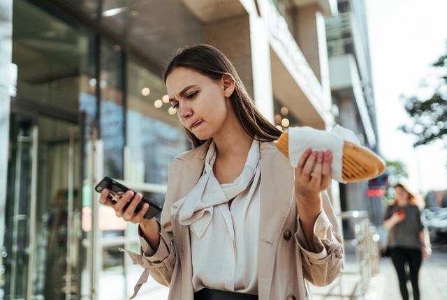 woman eating while looking at phone