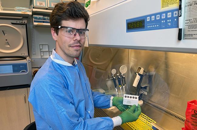 Malaria researcher Weston Staubus holds a card with dried blood spots collected during a study in Mali. RNA was extracted from more than 5,000 samples.