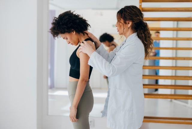 Physical therapist examines the neck of a young woman