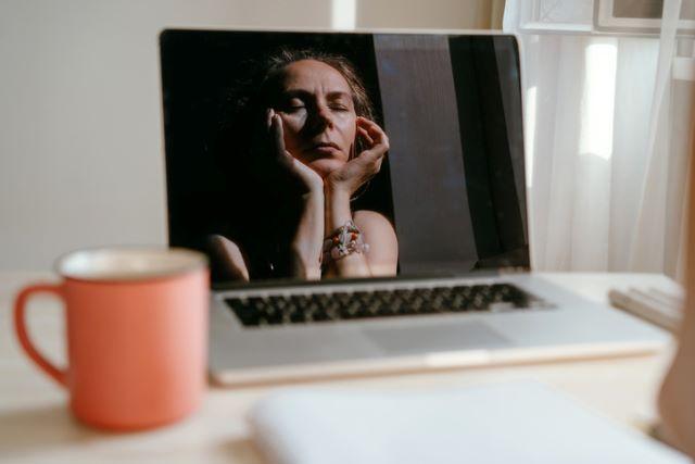 Woman, who has a headache, looking at the computer screen. 