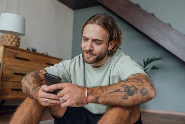 Image of a young man texting with a calm look on his face